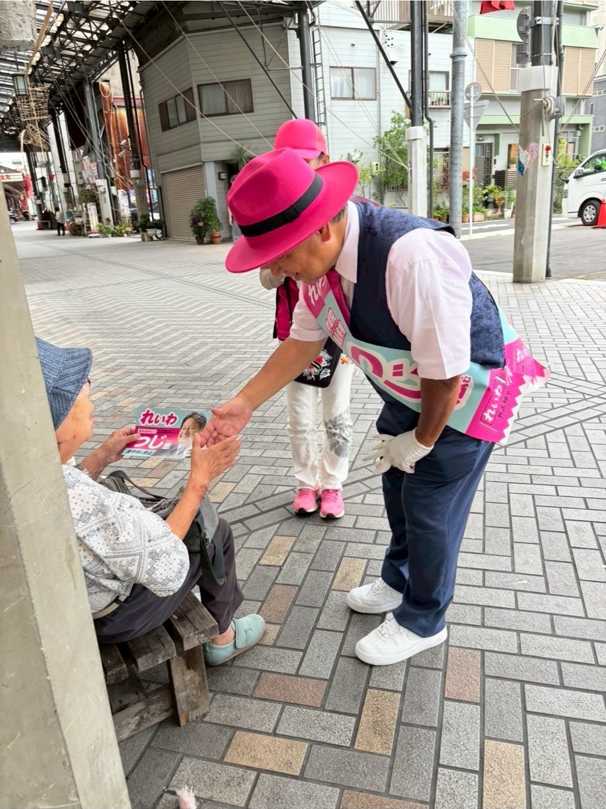 チラシを配り握手を交わす辻さん